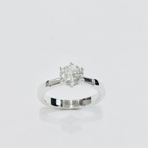 Solitario de oro blanco con diamante 1,25 quilates y baguette 0,30 quilates. Consultar precio.